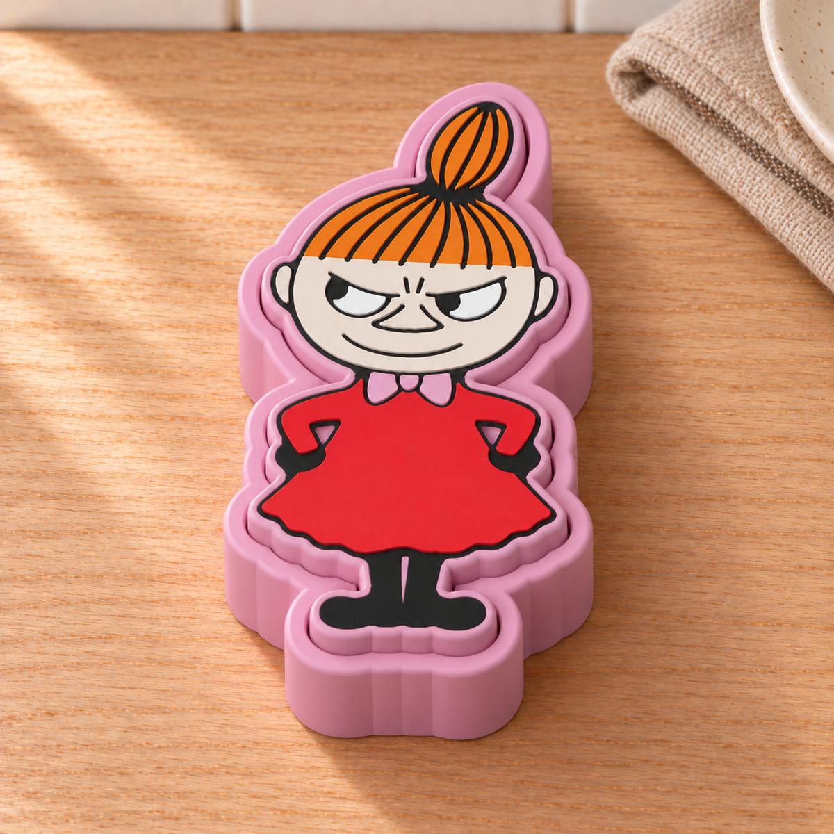 Little My fidget clicker with pink base and lid, orange hair and red dress in a Scandinavian kitchen.