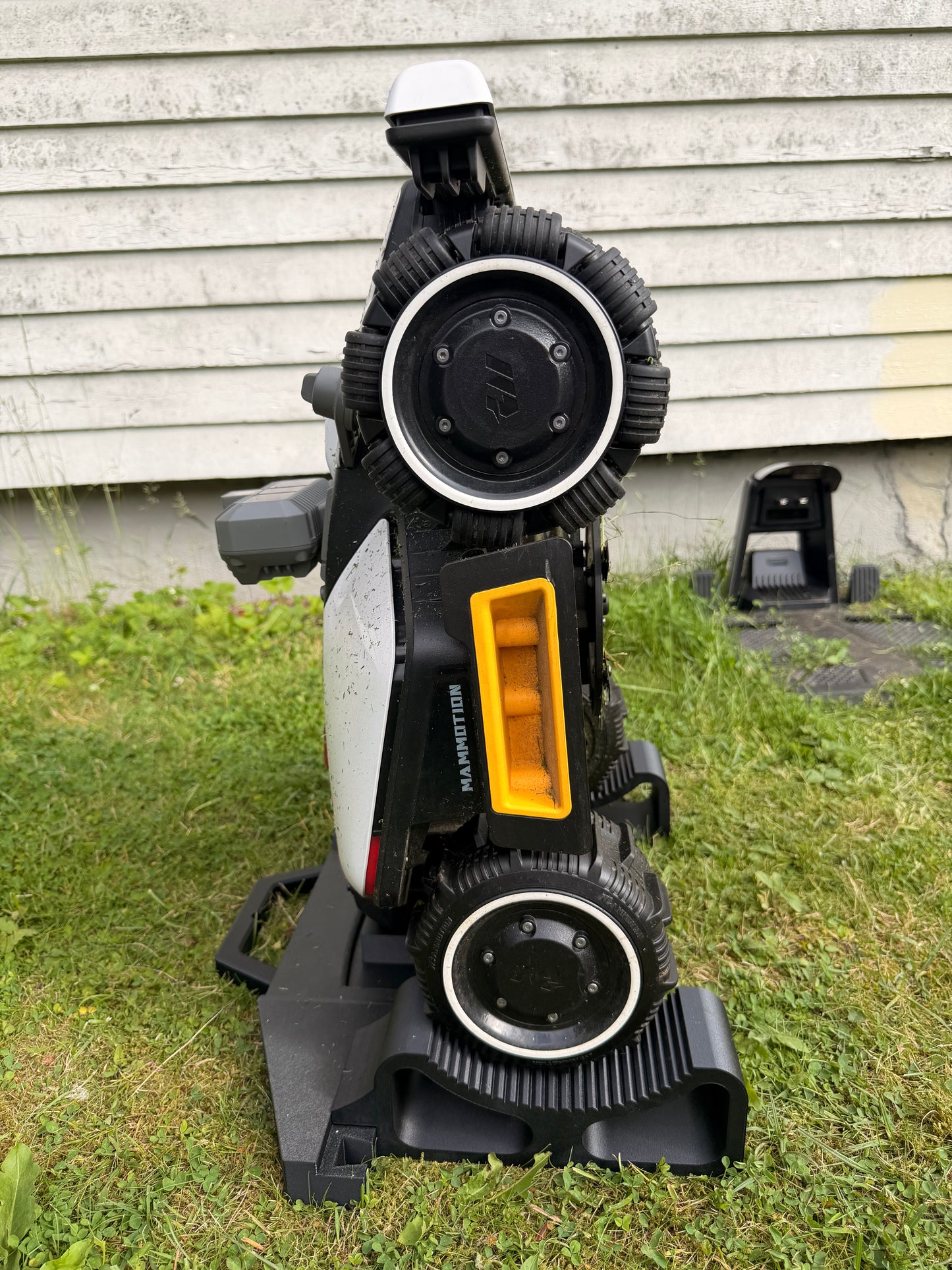 Mammotion Luba Mini robot mower held upright on the service and maintenance stand