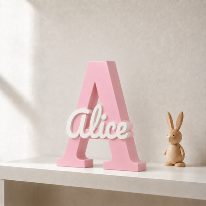 Pink 3D printed letter A name sign with the name Alice in white script, standing on a shelf