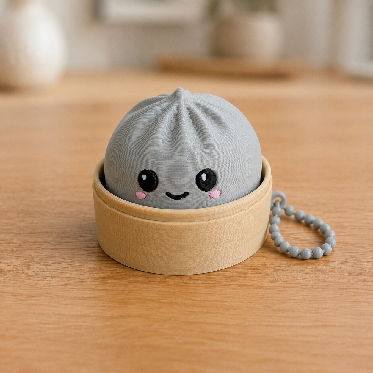 Ash Gray dumpling fidget clicker keychain in its bamboo steamer basket, with ball chain