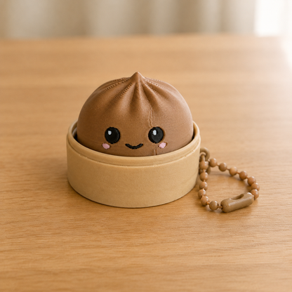 Caramel dumpling fidget clicker keychain in its bamboo steamer basket, with ball chain
