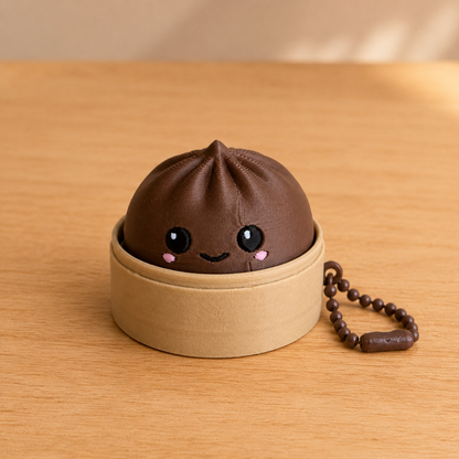 Dark Chocolate dumpling fidget clicker keychain in its bamboo steamer basket, with ball chain
