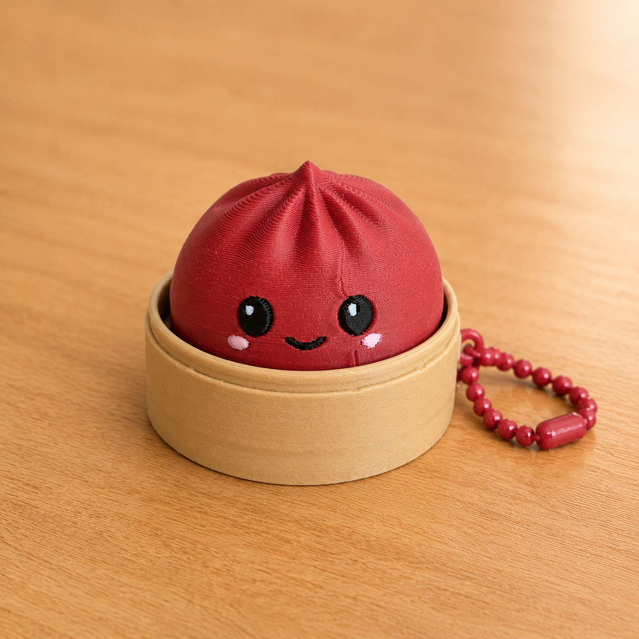 Dark Red dumpling fidget clicker keychain in its bamboo steamer basket, with ball chain