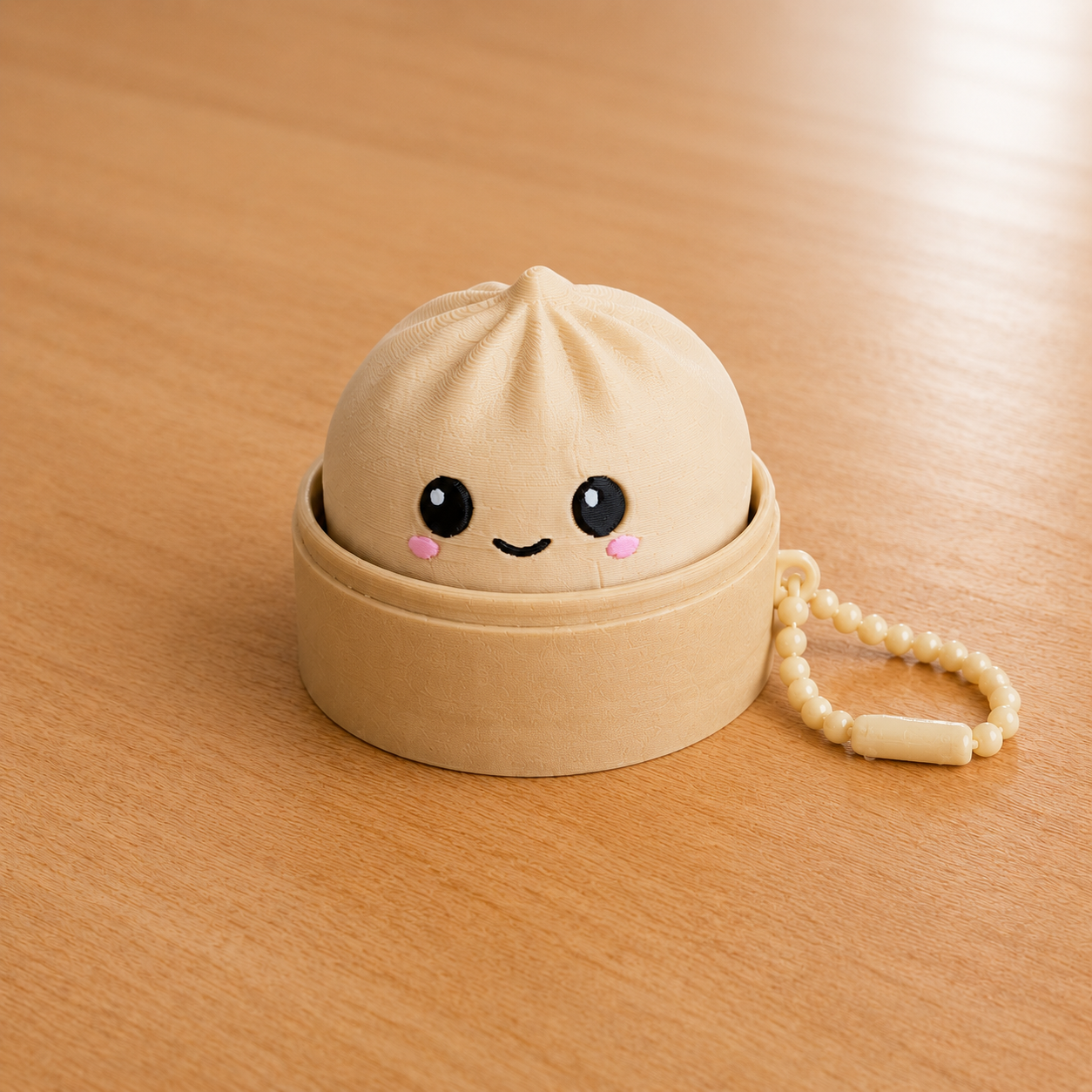 Desert Tan dumpling fidget clicker keychain in its bamboo steamer basket, with ball chain
