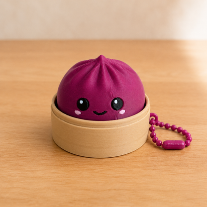 Plum dumpling fidget clicker keychain in its bamboo steamer basket, with ball chain