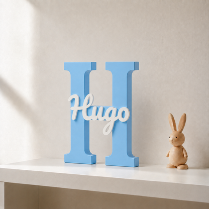 Light blue 3D printed letter H name sign with the name Hugo in white script, standing on a shelf