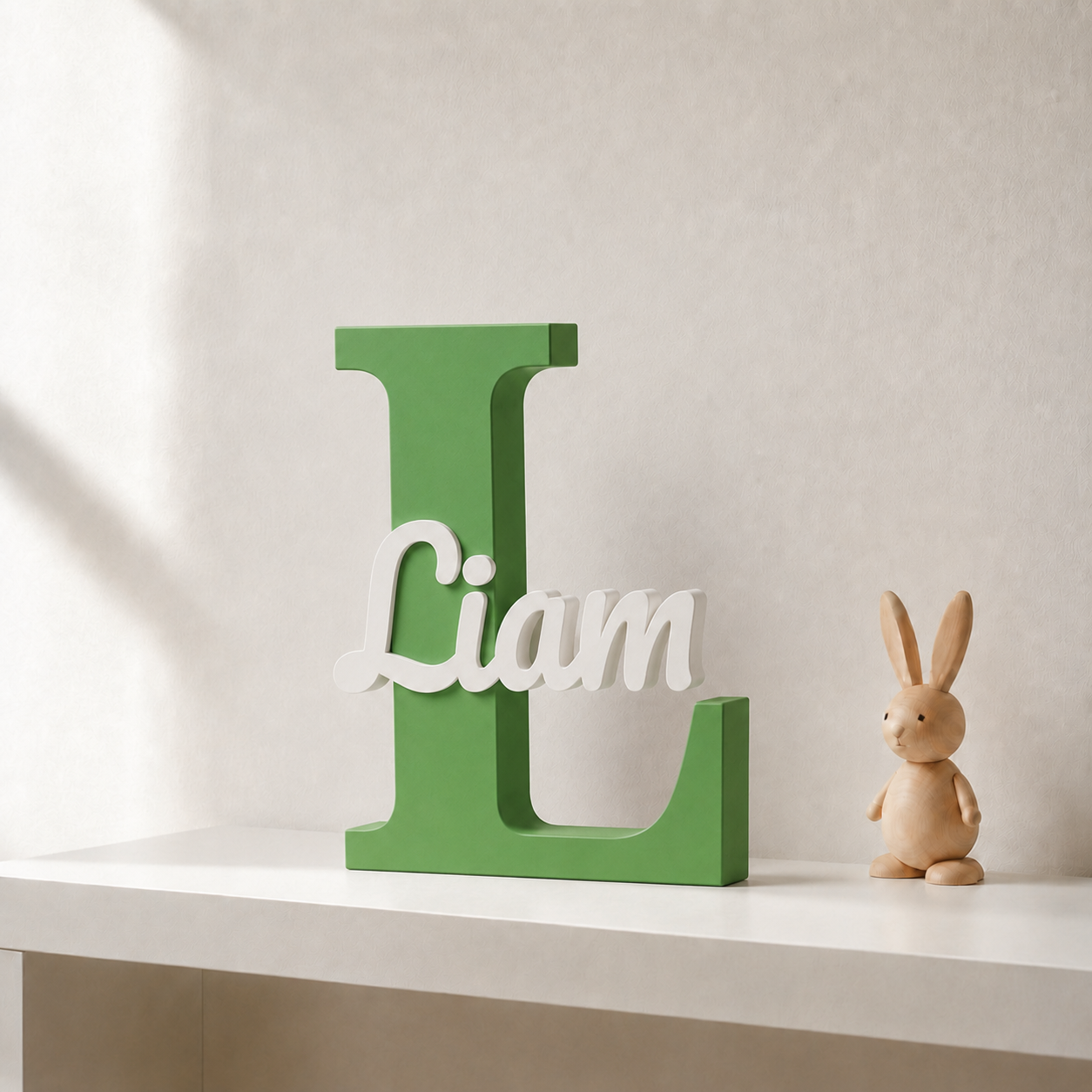 Green 3D printed letter L name sign with the name Liam in white script, standing on a shelf