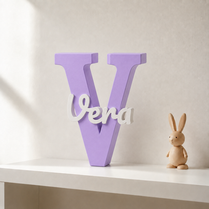 Purple 3D printed letter V name sign with the name Vera in white script, standing on a shelf