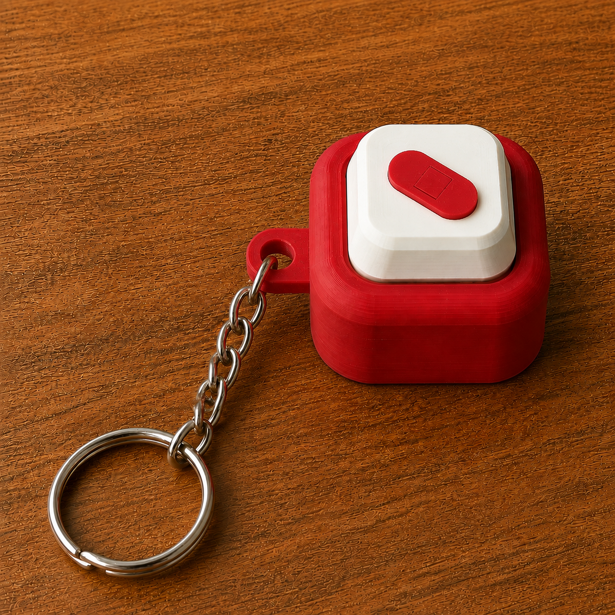 Red and white Hospital Clicker with a bandage design, raised white button, side loop, metal chain and split ring on a wooden surface.