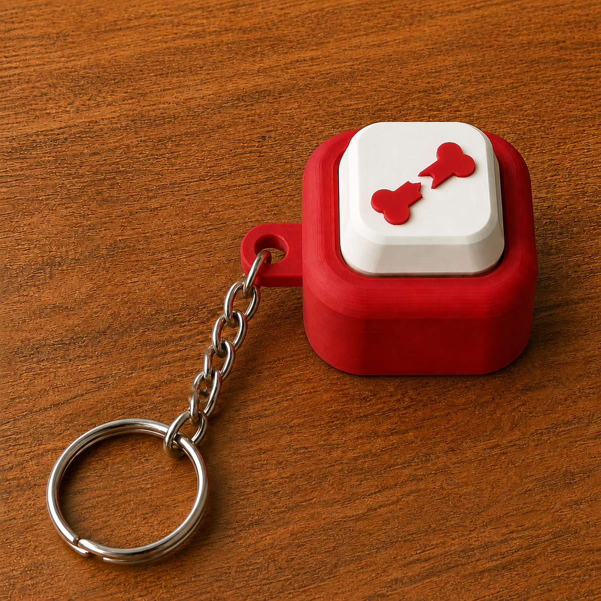 Red and white Hospital Clicker with a broken bone design, raised white button, side loop, metal chain and split ring on a wooden surface.