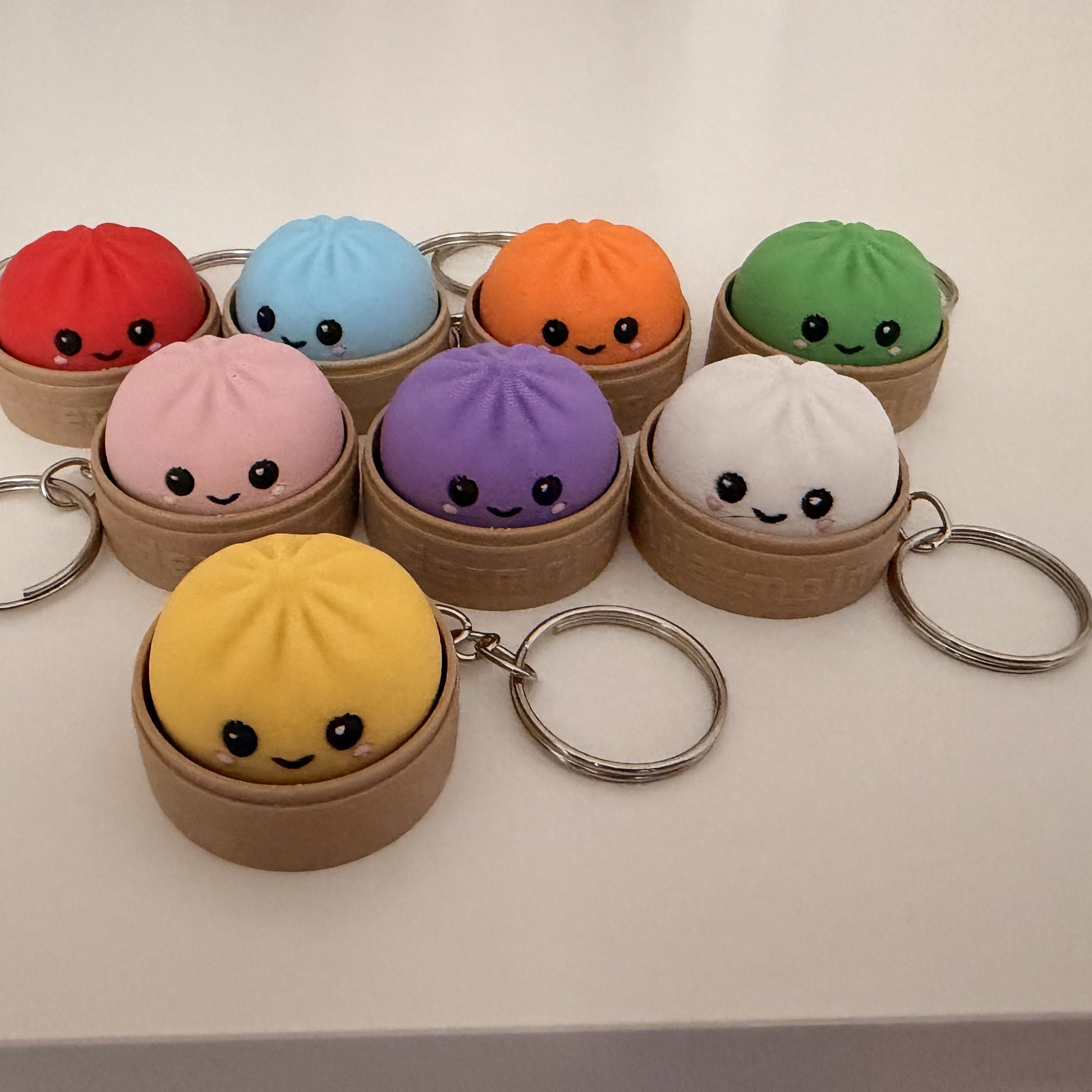3D printed dumpling fidget clicker keychains in eight colors, each in a bamboo-brown steamer basket