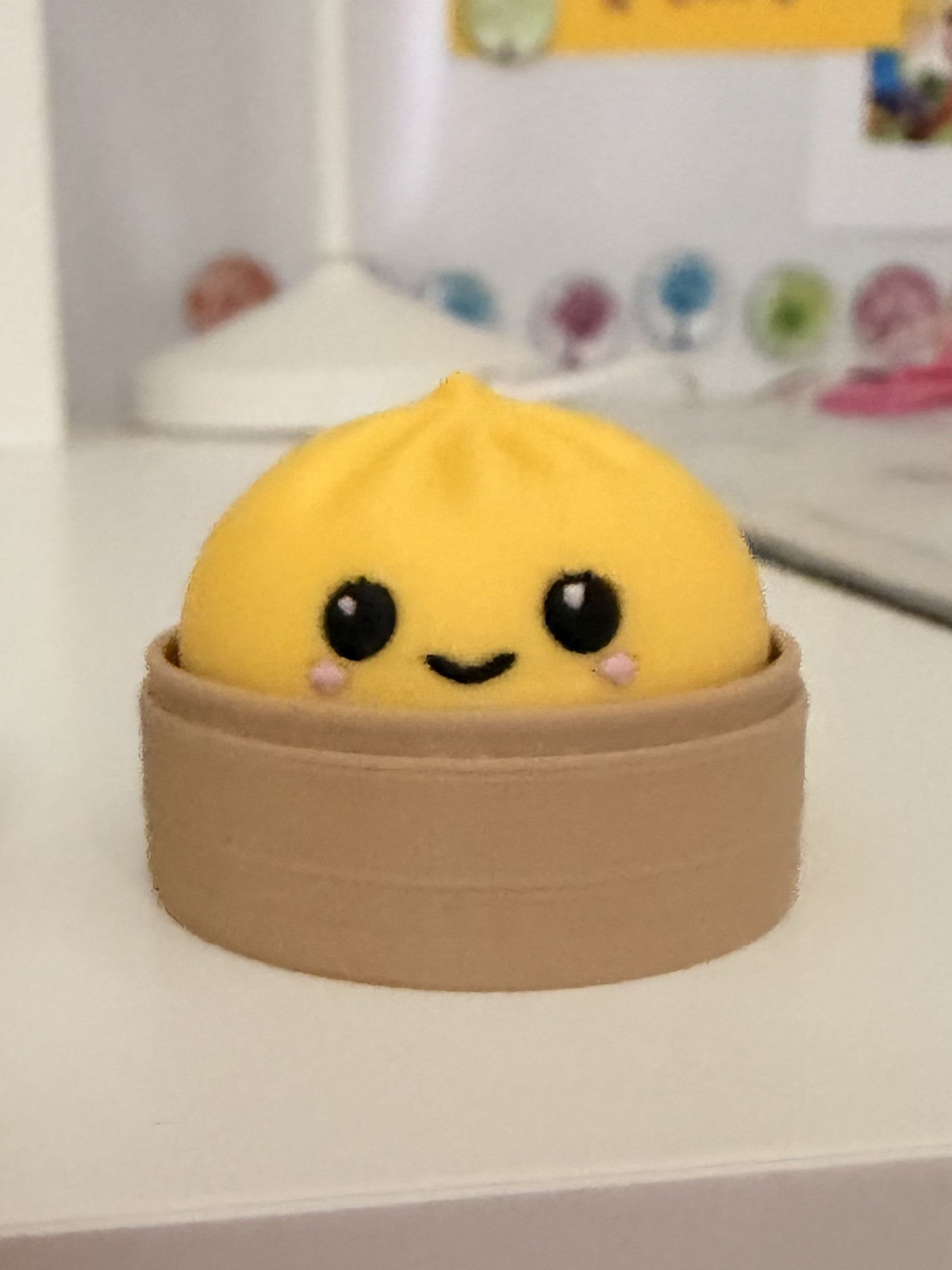 Yellow dumpling fidget clicker keychain with kawaii face in steamer basket, close-up