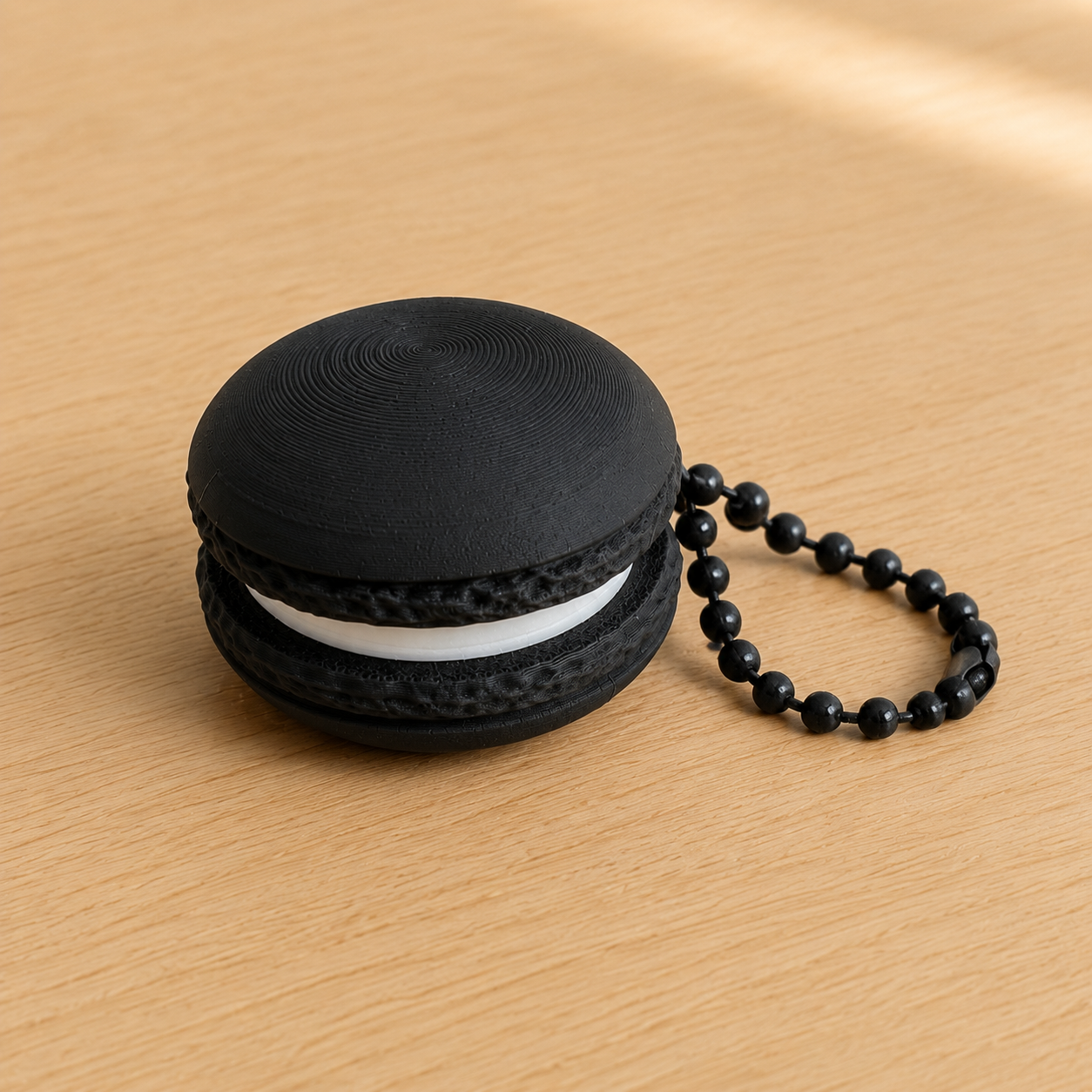 Charcoal 3D printed macaron fidget clicker keychain with white filling and matching ball chain
