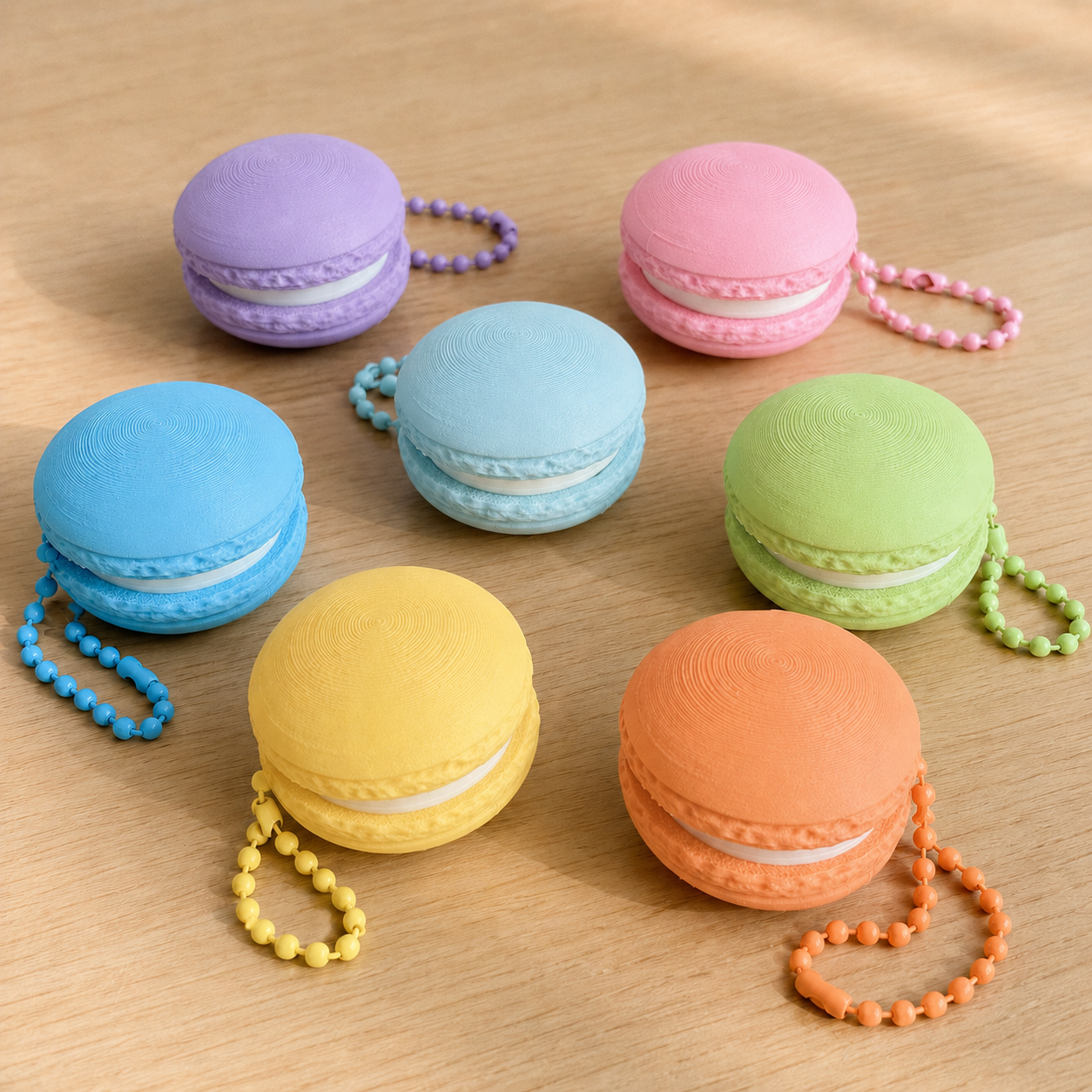 Seven 3D printed macaron fidget clicker keychains in pastel colours with matching ball chains