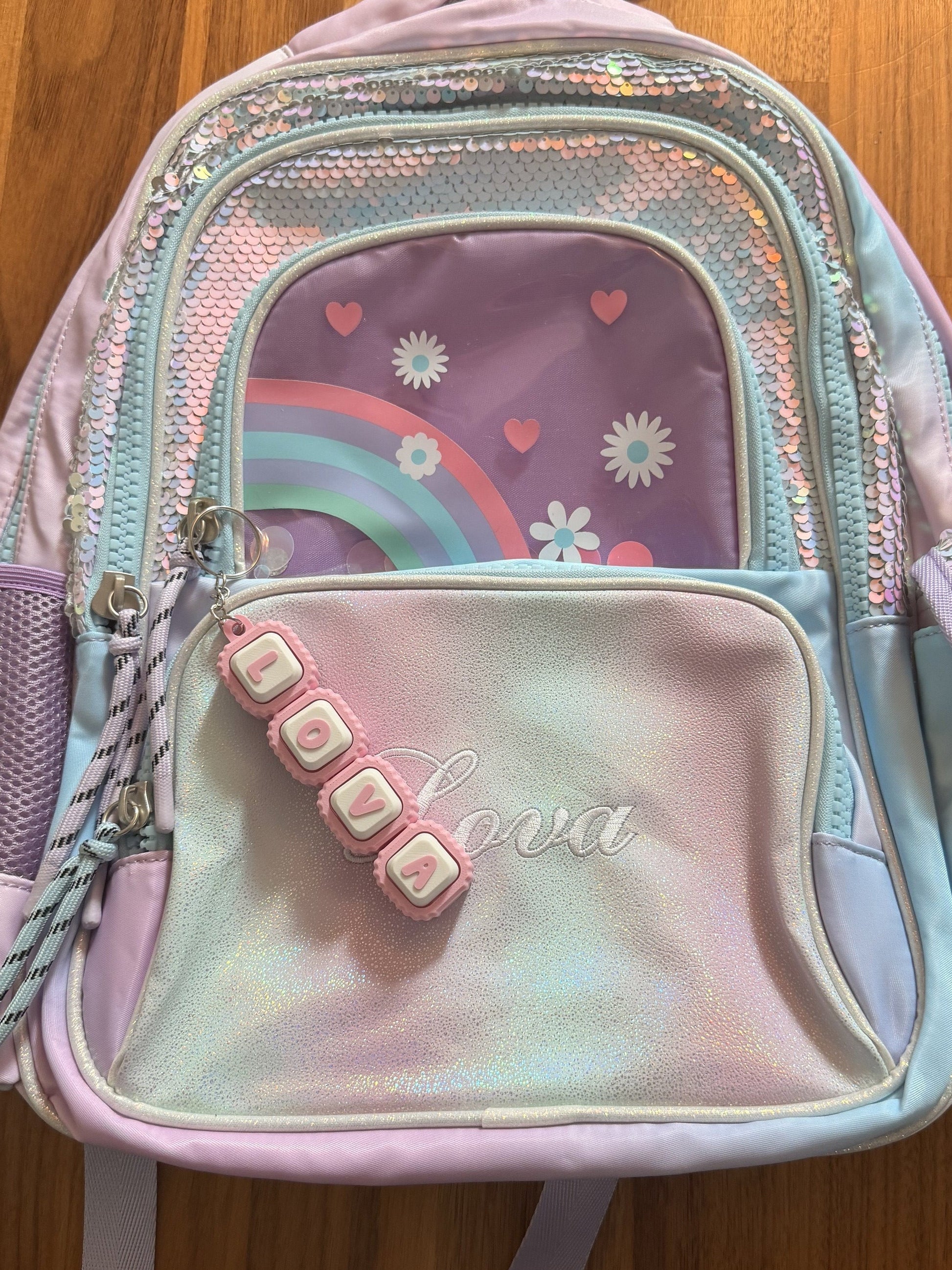 Personalized name tag clicker keychain clipped to a pastel backpack