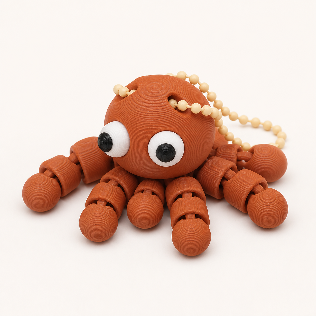 Terracotta articulated octopus flexi keychain with white eyes, on a ball chain